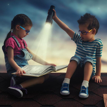 2 Kinder mit Brille, ein Mädchen liest, Junge hält Taschenlampe